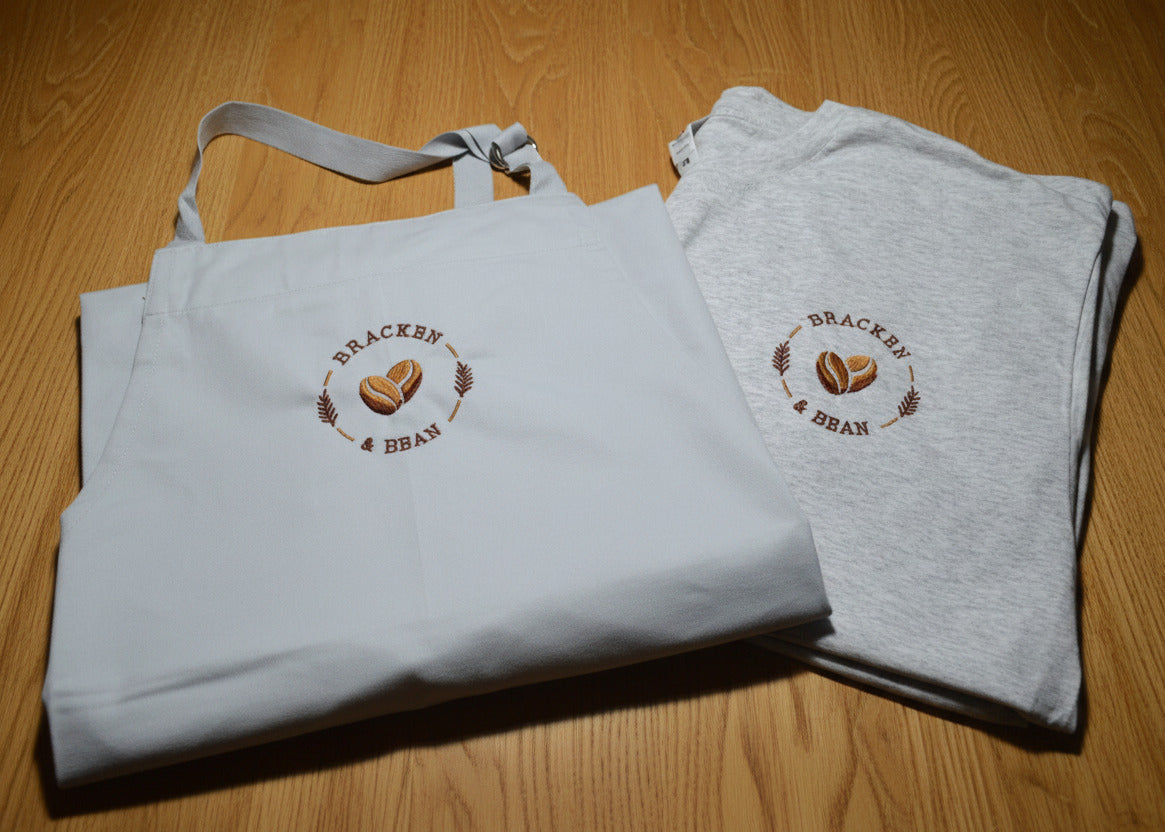 grey apron and T-Shirt with a brand logo on a desk.