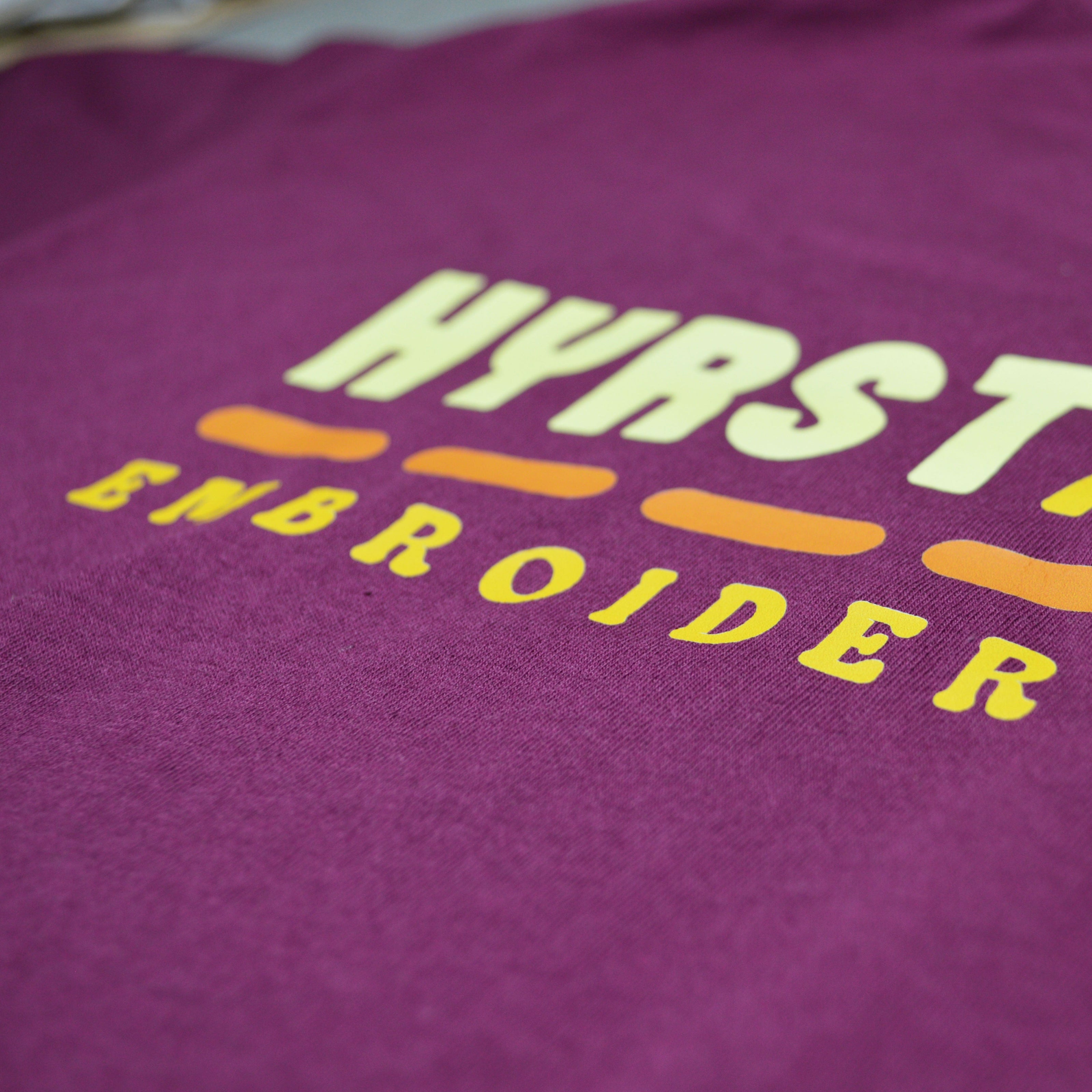 Close-up of a purple fabric with colorful text on a plain background