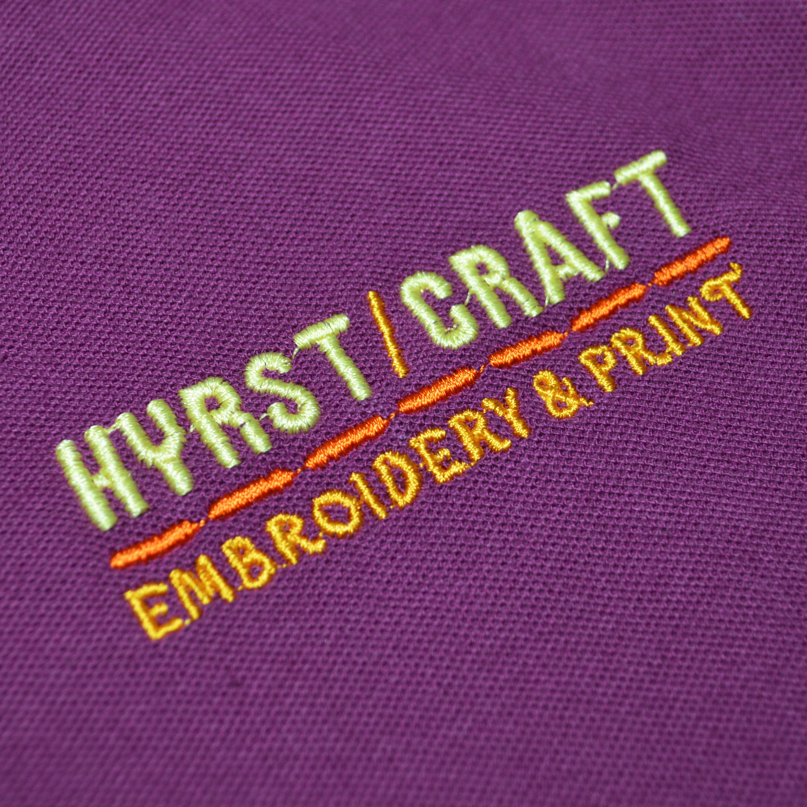 Embroidered logo on a purple polo shirt with 'HYRST/CRAFT' and 'EMBROIDERY & PRINT'.
