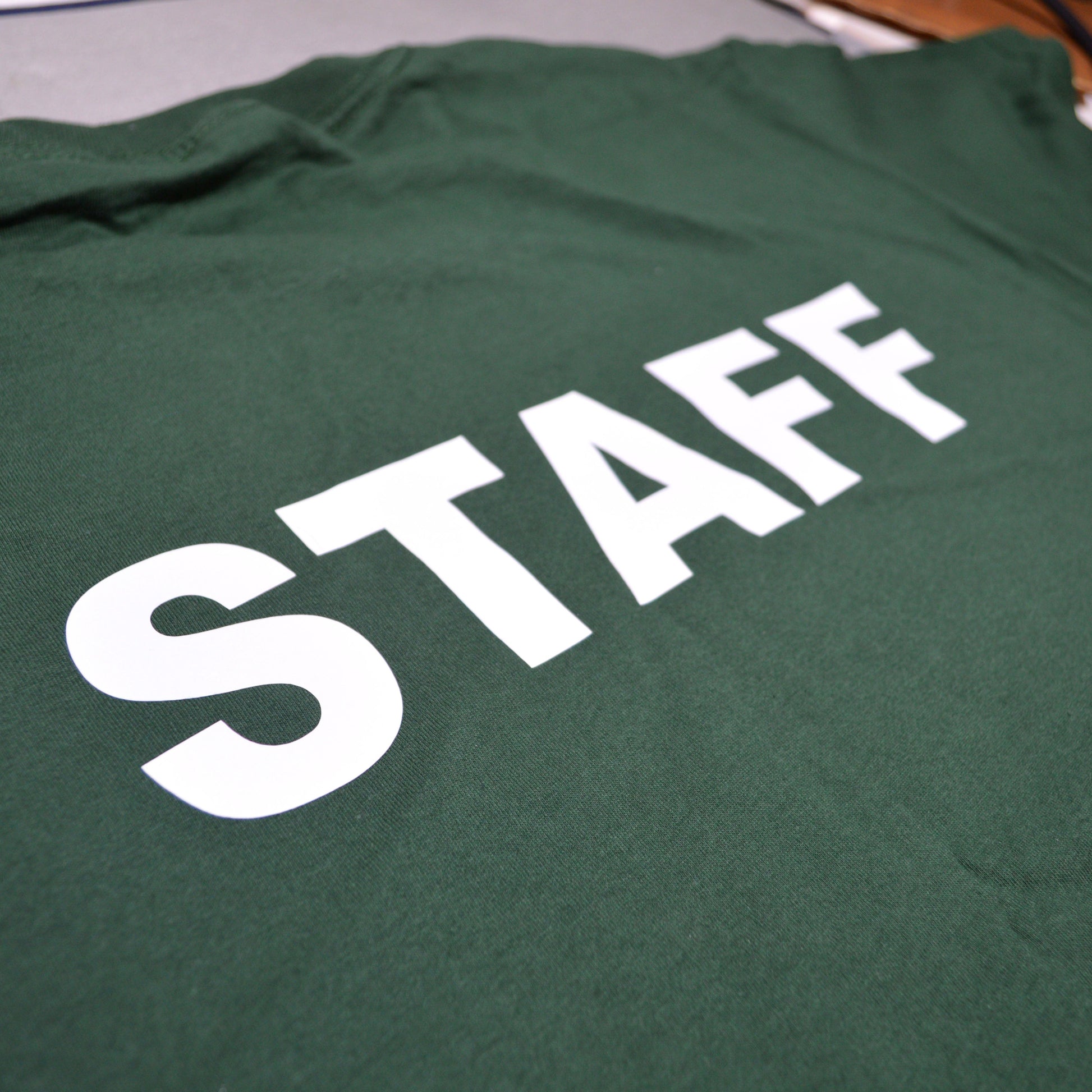 Green shirt with 'STAFF' printed in white on a plain background